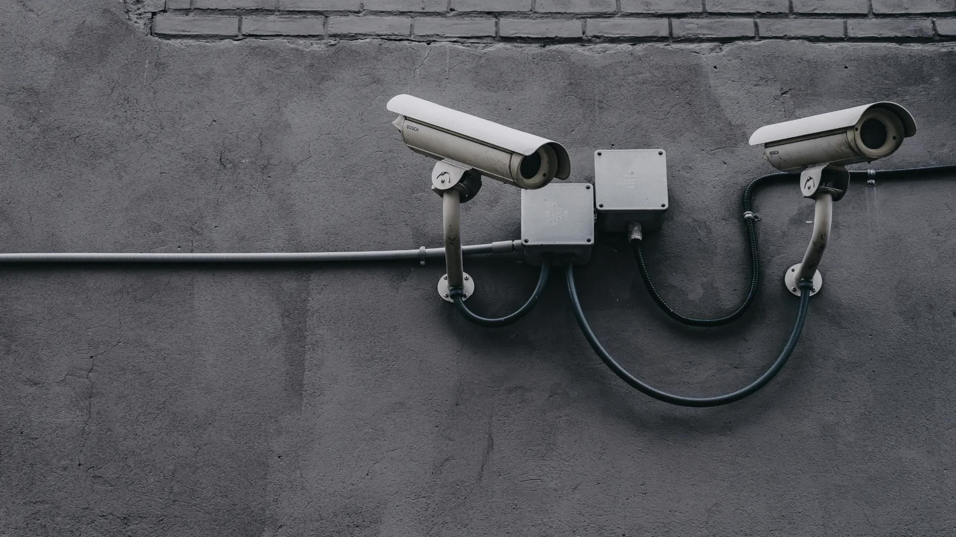 Two surveillance cameras on a grey beton wall